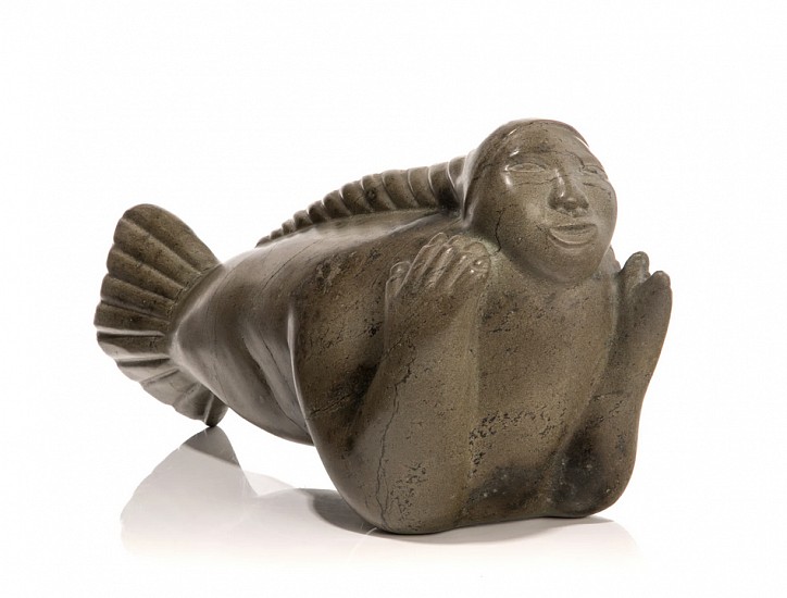 Kenojuak Ashevak (attributed), Swimming Sedna with Plaited Hair, 1970-1975
Stone, 9 1/2 x 20 x 6 1/2 in. (24.1 x 50.8 x 16.5 cm)
In her sculptural works, Kenojuak's subjects were much the same as those found in her prints and drawings. Contrastingly, however, her carvings are much more solid and bulky than the more embellished style of her graphic works. Conceived of in the distinctive Markham Bay stone, the work depicts the Sea Goddess, Sedna, swimming through the Arctic waters with her hair gracefully streamlining down her back in a great plait.

For more information on the Sedna legend, see https://www.alaskaonmadison.com/exhibition/3/press_release/

Although there are very few known sculptures of people signed by Kenojuak, the Markham Bay stone and the eyes on this sedna are consistent with a number of Kenojuak sculptures. For works by Kenojuak with strikingly similar nose and lips, see https://www.invaluable.com/auction-lot/kenojuak-ashevak-inuit-quartzite-woman-walrus-cub-70-c-68e4fd485e?objectID=135429400&algIndex=undefined&queryID=51dbbb57c1e2e65a2da8ea34a2b8200f  and https://www.invaluable.com/auction-lot/kenojuak-ashevak-1927-e7-1035-cape-dorsetwoman-an-310-c-a7d1ddd2f3?objectID=74447139&algIndex=undefined&queryID=dc3543c2517d36001f7eb2eca1fcc567  .

References: For other examples of Kenojuak's sculptural works, see Jean Blodgett, Kenojuak, (Toronto: Firefly Books / Mintmark Press Ltd., 1985), figs. xxix-xxiv, pp. 67-70.  See fig. xxix for another depiction of the Sea Goddess. 
03568-1